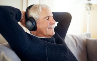 Senior citizen with headphones listening to podcast.