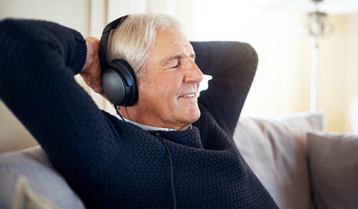 Senior citizen with headphones listening to podcast.